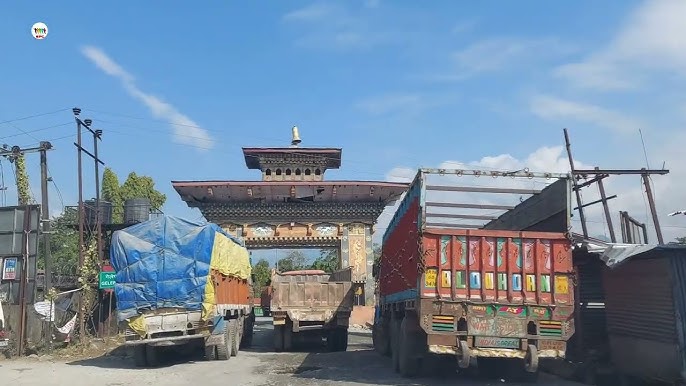 A cross-border checkpoint with trucks and goods in transit between India and Bhutan.